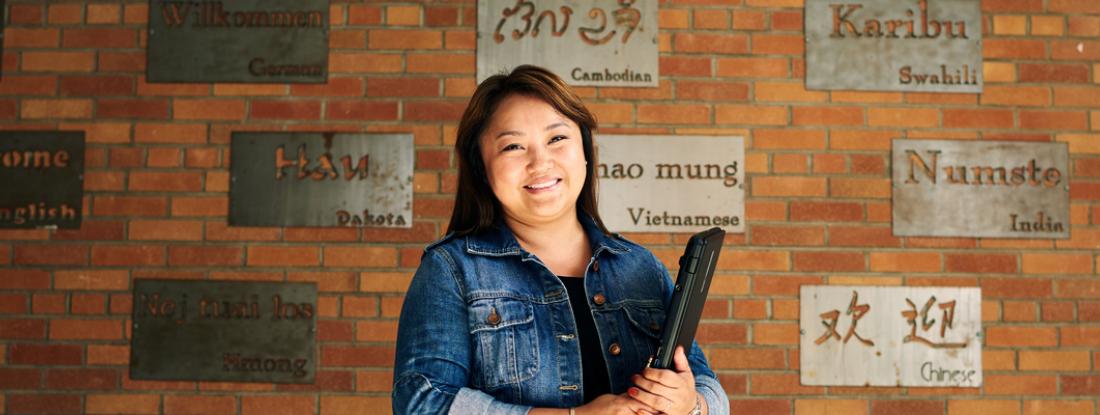 Hamline School of Education Alumni Student, Nouly, holding a book in front of wall 