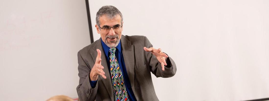 A person speaking in front of a whiteboard at Hamline in a history class