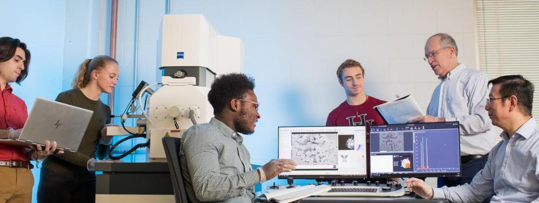 Group of Hamline students and professors using an electron microscope