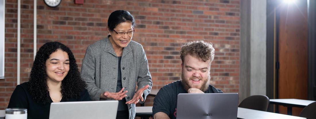Hamline Professor with students lokking to their laptops 