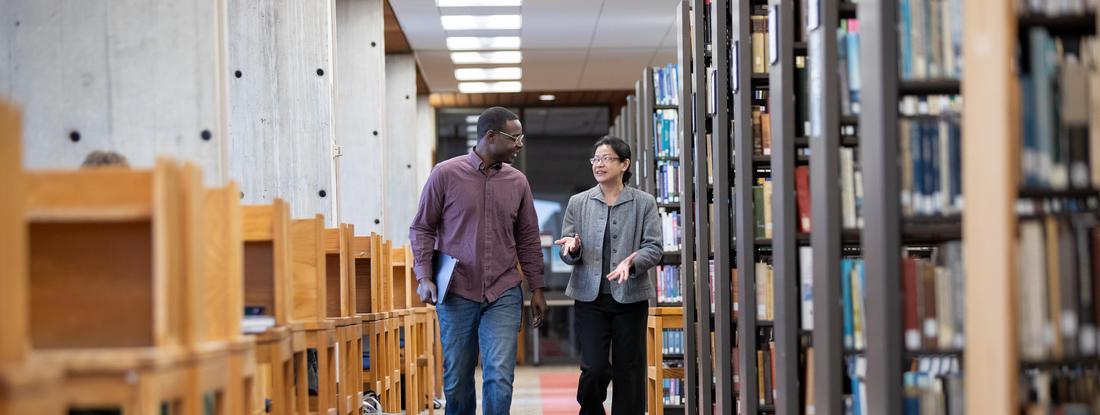 Hamline Student and Professor walking in Bush library