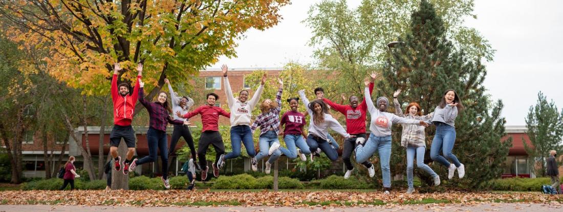 A group of Hamline students in a line outside, jumping for joy