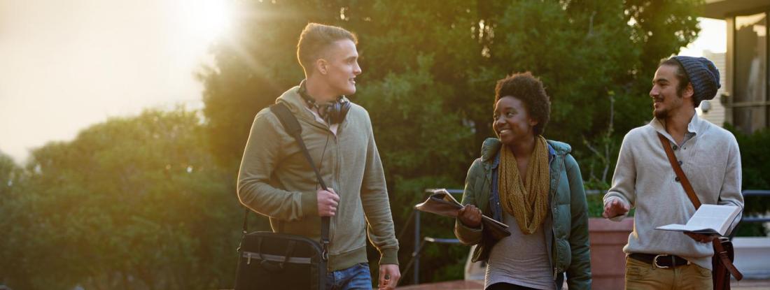 Three people walking outside smiling and talking