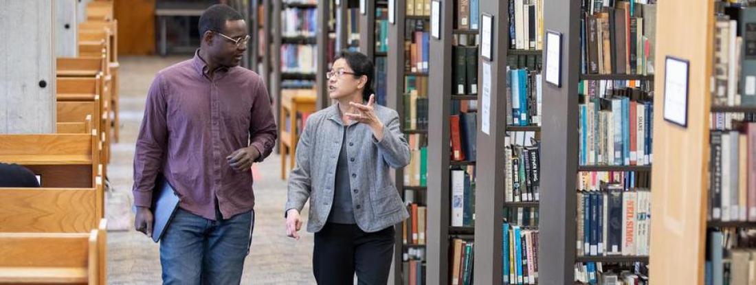 Hamline professor and student talking in the library