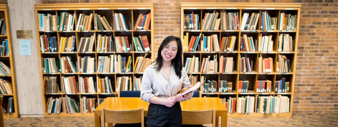 Photo of Mien Le in front of library bookshelves