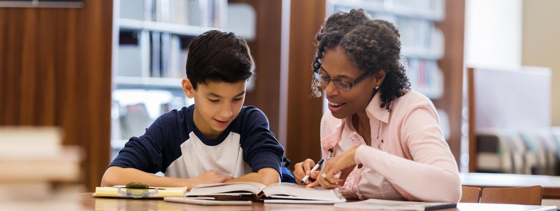 Photo of a young student and teacher working together on schoolwork