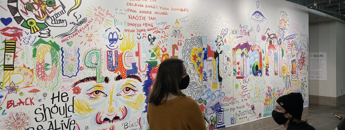 Hamline students stand in front of a collage wall titled "bouquet of humanity"