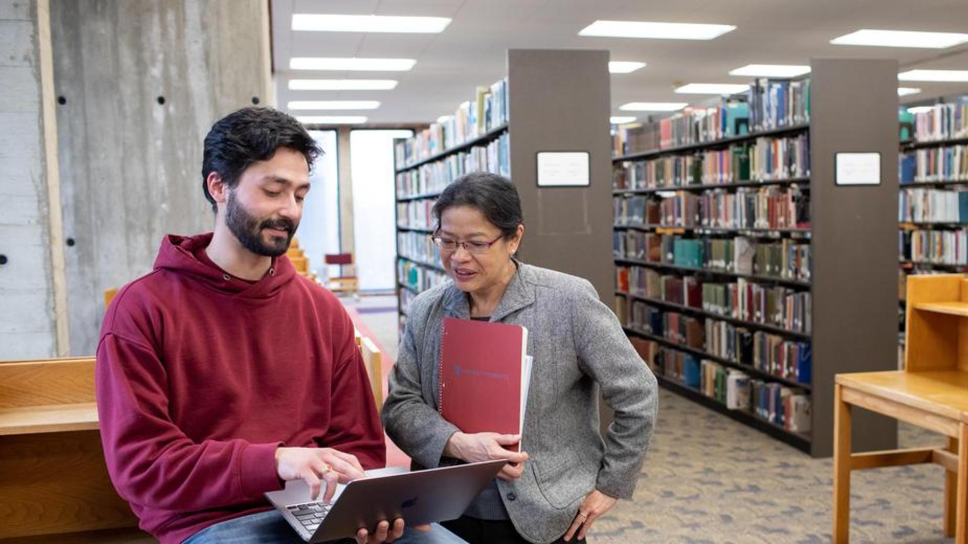Ashwin Kushwaha talking with a Hamline professor in Bush Library