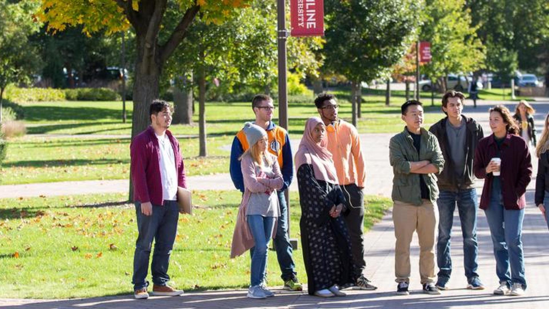 A group of prospective Hamline students standing outside on campus with a tour guide