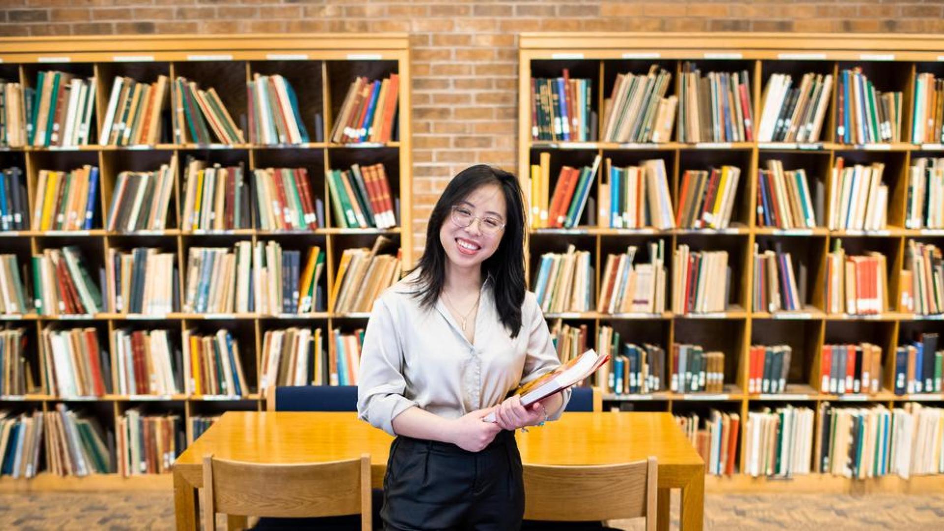 Photo of Mien Le in front of library bookshelves