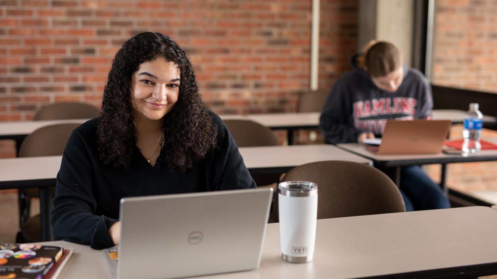 Student smiling using a laptop