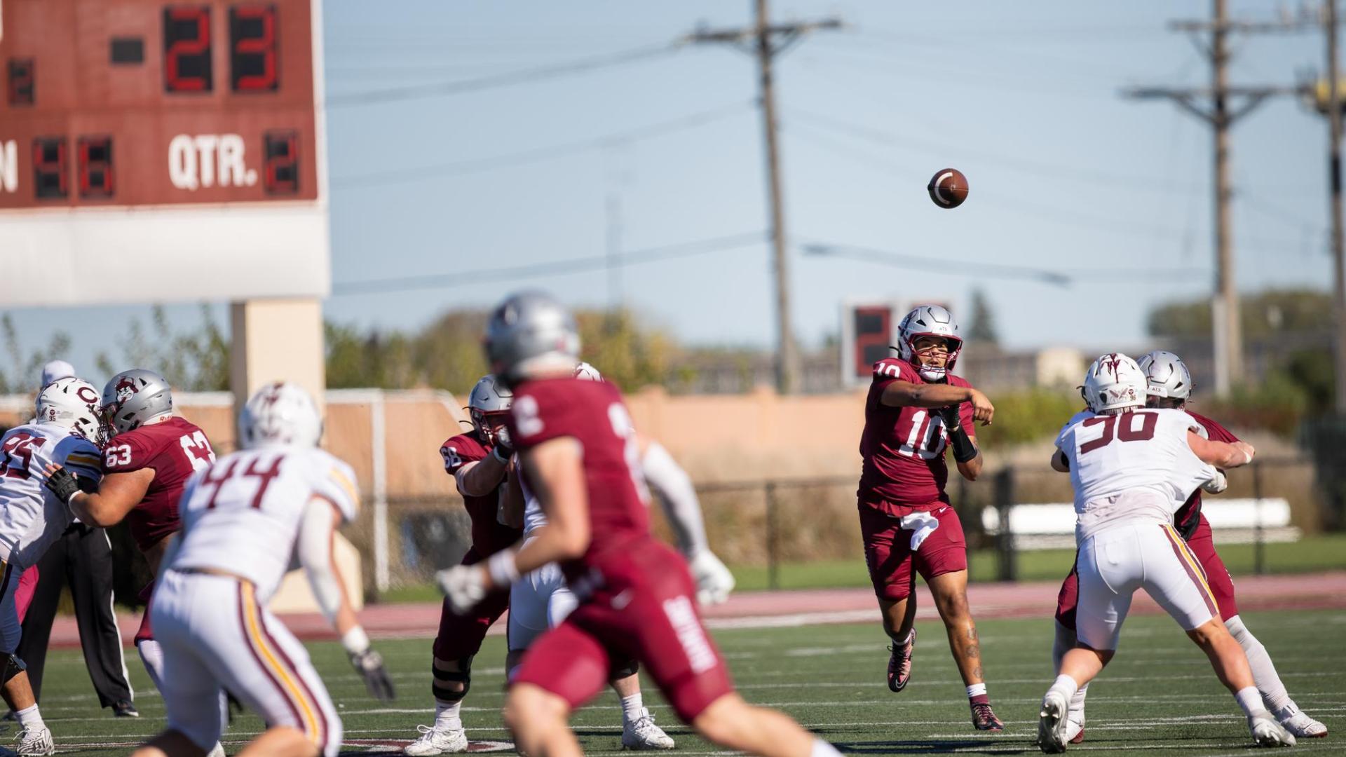 Hamline football player makes a pass in an Alumni Weekend game
