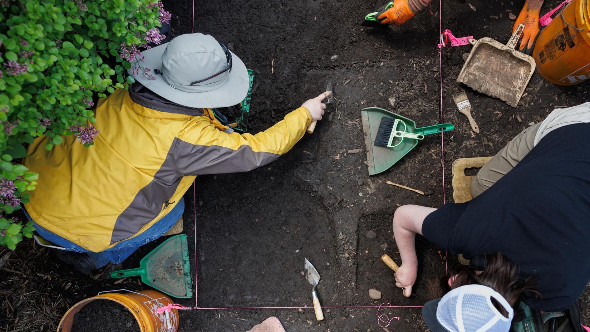Students digging and brushing with small implements in an archaeology class