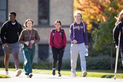 Group of Hamline students walking in front of Old Main in fall