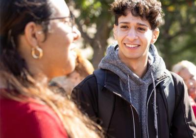 Hamline student in grey hoodie smiling at student with earrings
