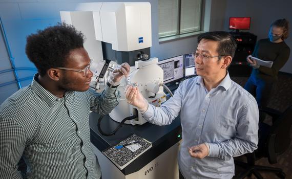 Hamline student and professor looking to a microscope