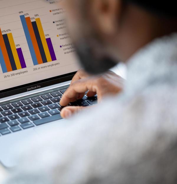 Man typing on a laptop displaying a bar chart
